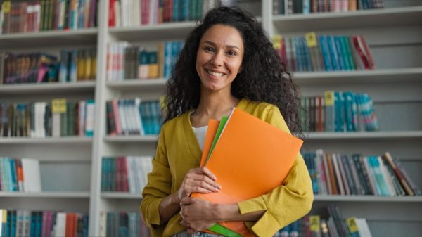 insegnante-scuola-felice-fogli-in-mano-per-viaggio-con-minori.